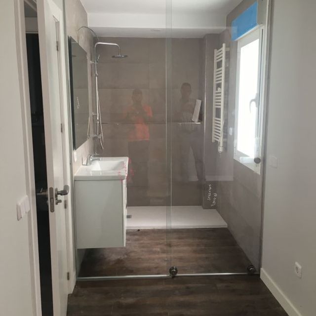 Un baño con ducha a ras de suelo y lavabo.