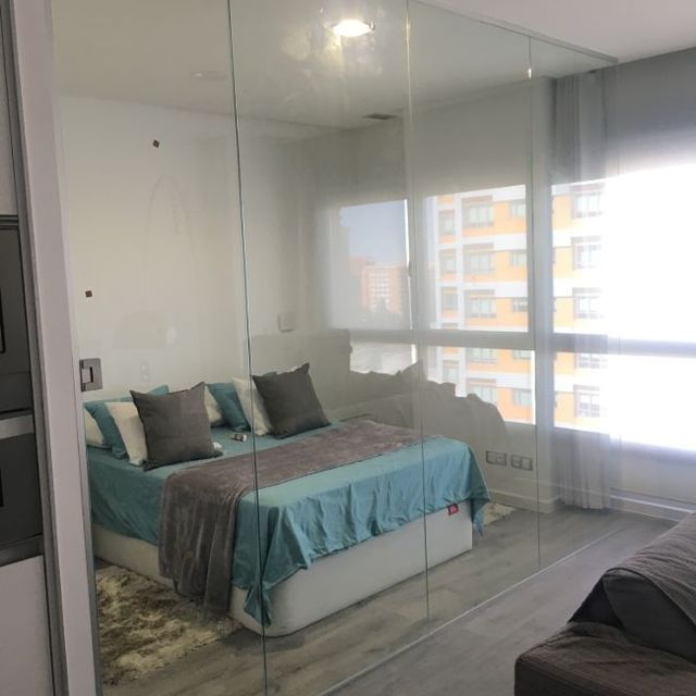 Un dormitorio con una cama detrás de una pared de cristal.