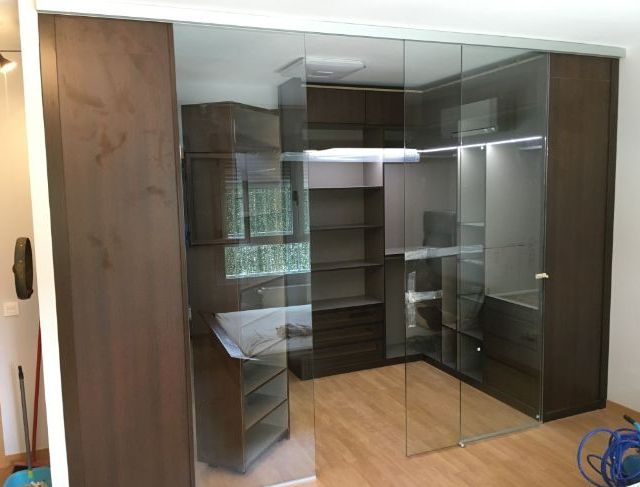 Un vestidor con puertas corredizas de vidrio y gabinetes de madera.