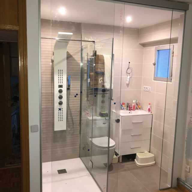 Un baño con inodoro, lavabo, ducha y puertas corredizas de cristal.