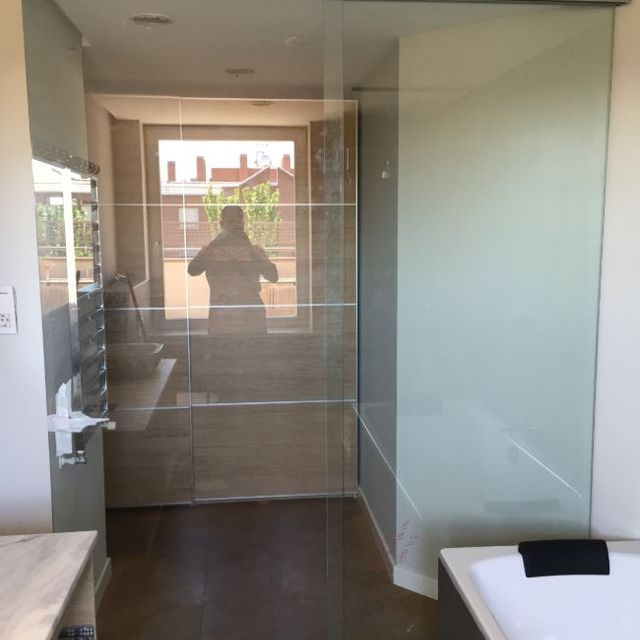 Un baño con el reflejo de una persona en el espejo.