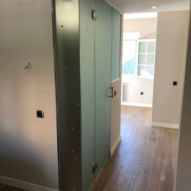 Un pasillo con una puerta de cristal y una ventana.