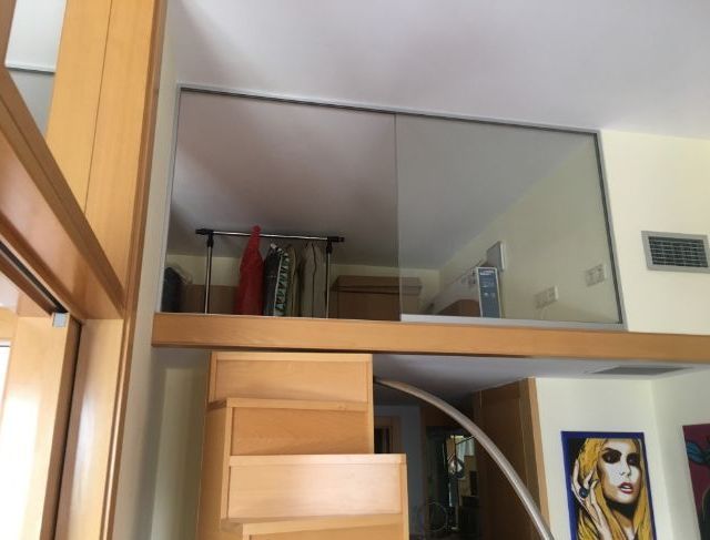 Una habitación con una escalera y un cuadro de una mujer en la pared.