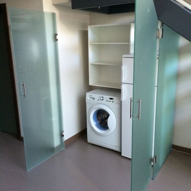 Una lavadora y una secadora están en un armario con puertas de vidrio.