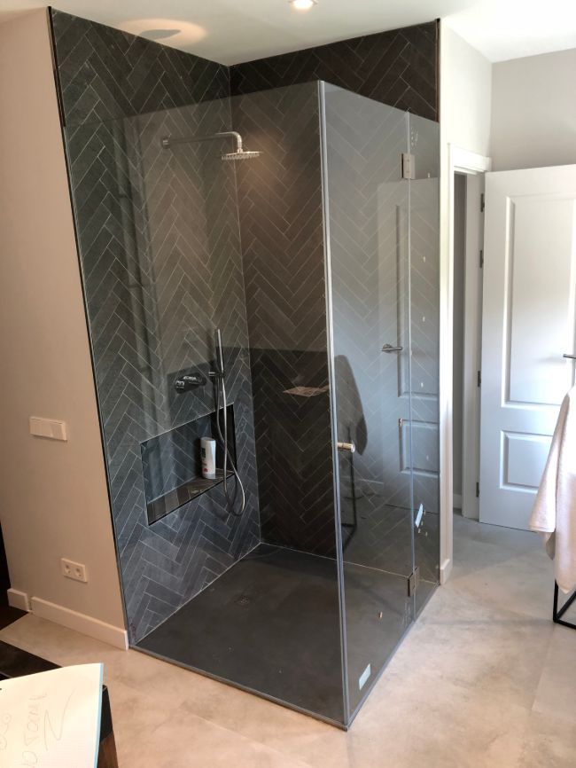 Un baño con ducha a ras de suelo y puerta de cristal.