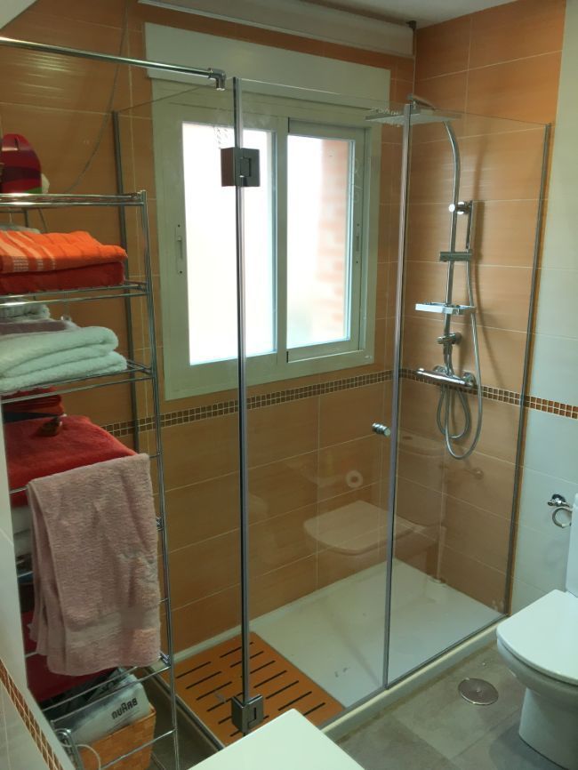 Un baño con ducha a ras de suelo y un inodoro.