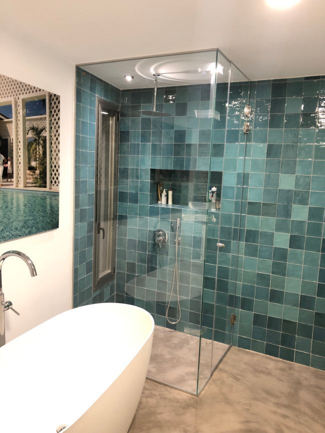 Un baño con azulejos azules y ducha a ras de suelo.