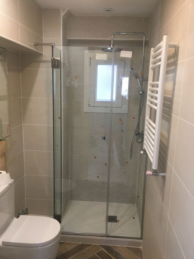 Un baño con inodoro, ducha y toallero.