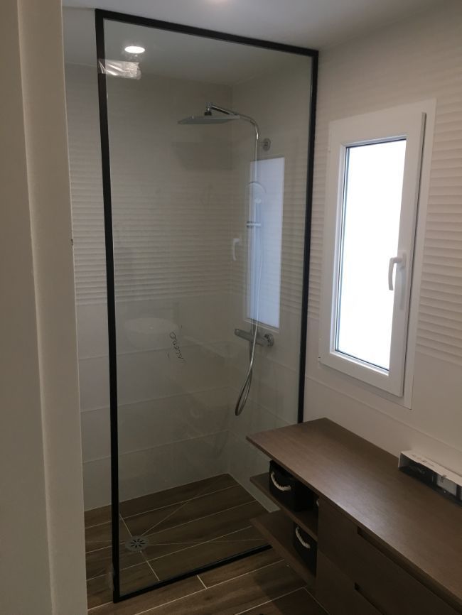 Un baño con ducha a ras de suelo y ventana.