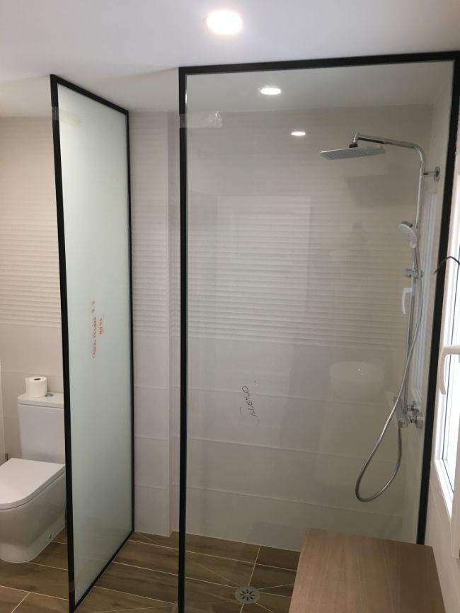 Un baño con ducha a ras de suelo y un inodoro.