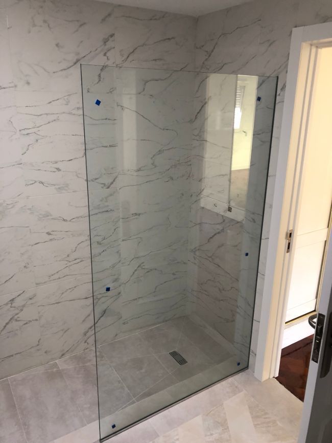 Un baño con ducha a ras de suelo y puerta de cristal.