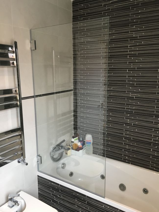 Un baño con bañera y puerta de ducha de cristal.