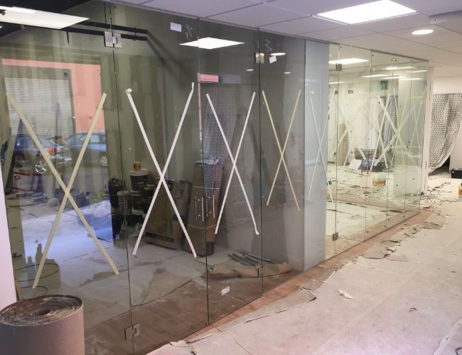 Una habitación con muchas paredes de cristal y algunas cajas en el suelo.