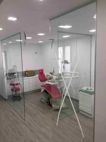 Un consultorio dental con un sillón dental y una pared de cristal.