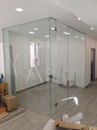 Una habitación con muchas paredes de cristal y cajas en el suelo.