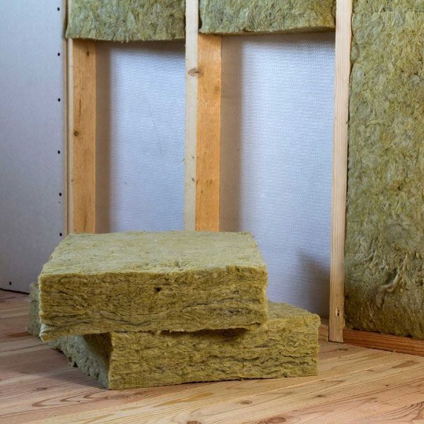 Una pila de lana de roca está colocada sobre un piso de madera frente a una pared.