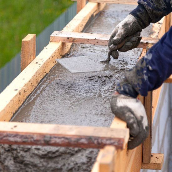 Una persona está usando una paleta para esparcir hormigón sobre una viga de madera.