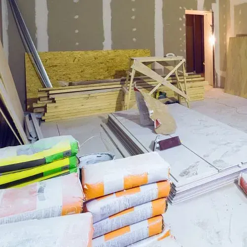 Una habitación en construcción con muchos sacos de cemento en el suelo.