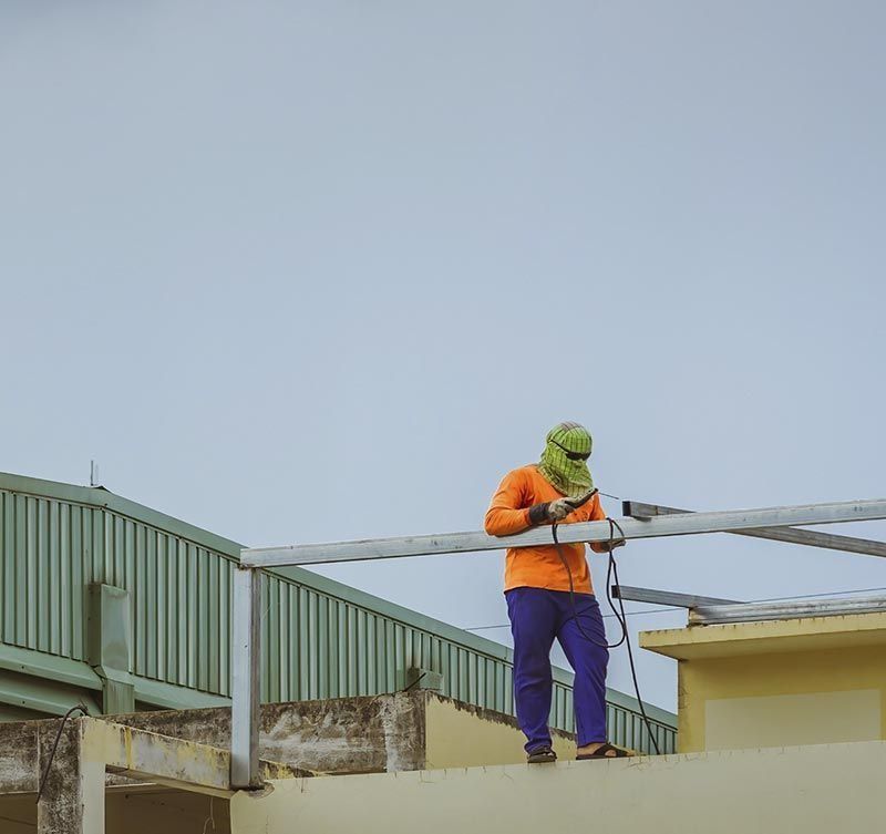 Un hombre está trabajando en el tejado de un edificio.