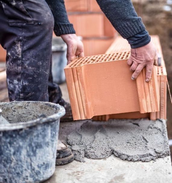 Un hombre está construyendo un muro con ladrillos y cemento.