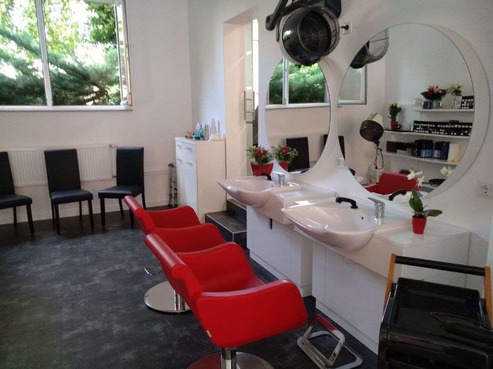 Waschbecken und rote Stühle im Friseursalon Nadine Jucha