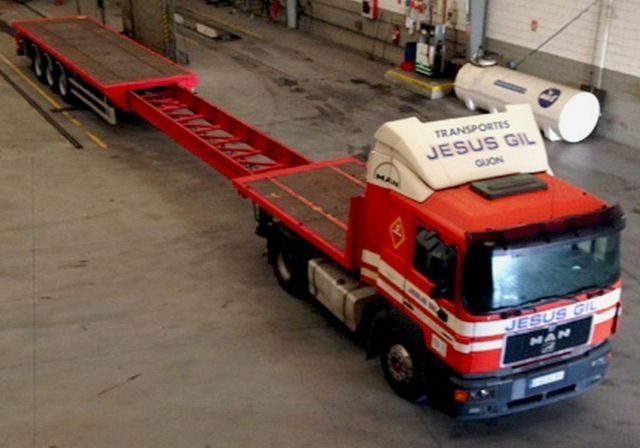 Un camión de aceite de Jesús rojo y blanco está estacionado en un garaje