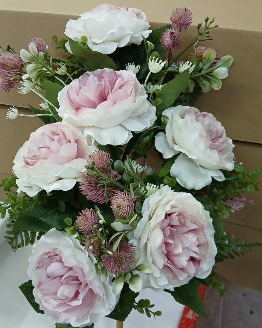 Ramo de rosas rosa pálido y blancas con follaje en una caja de cartón.