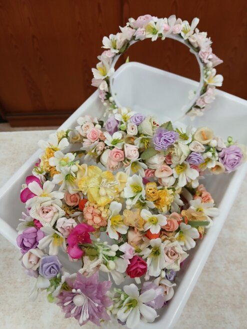 Arreglo floral en tonos pastel en una bandeja blanca con un aro floral y una pequeña tarjeta blanca.