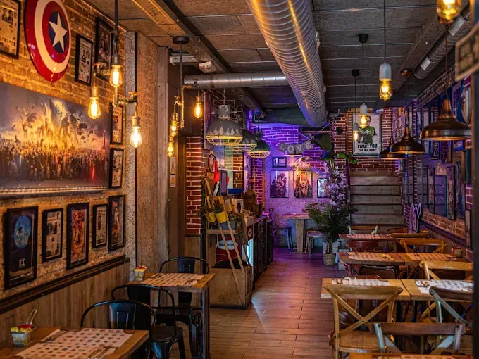 Un restaurante con mesas y sillas y un escudo del Capitán América en la pared.