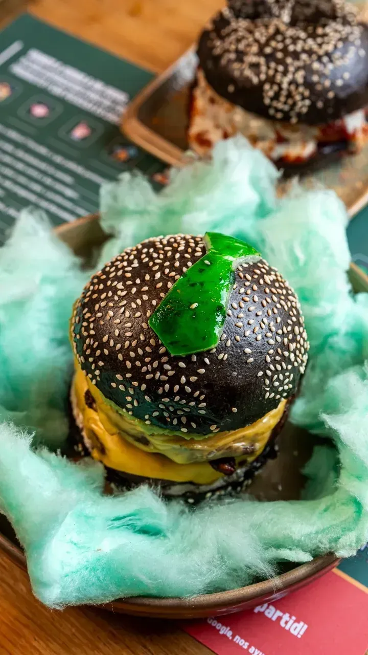 Un primer plano de una hamburguesa en un plato con algodón de azúcar.