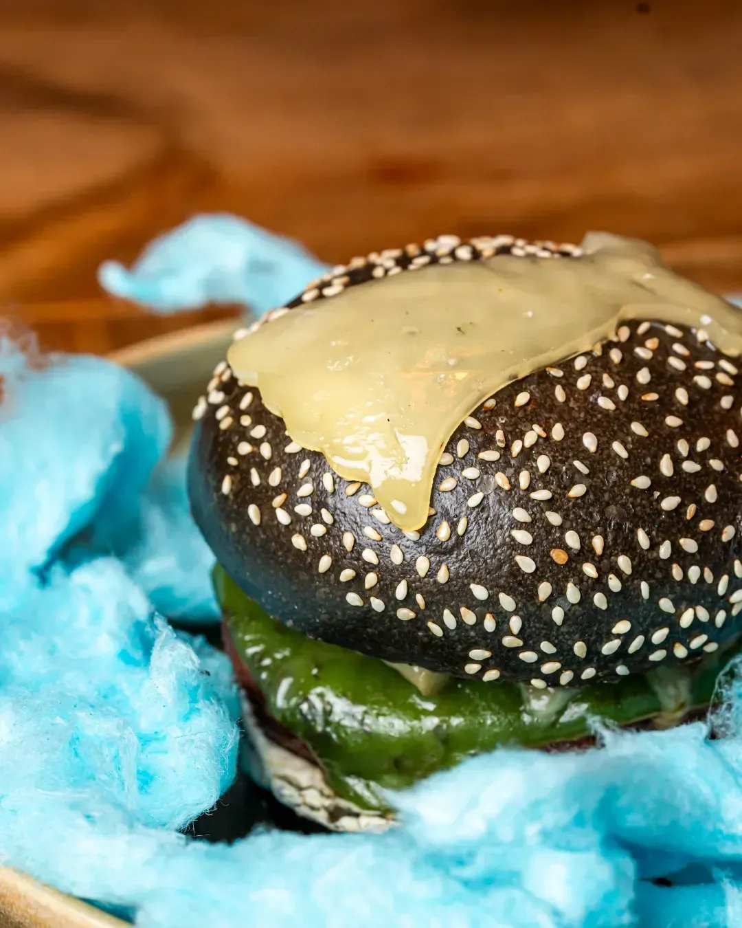 Un primer plano de una hamburguesa con algodón de azúcar al fondo.