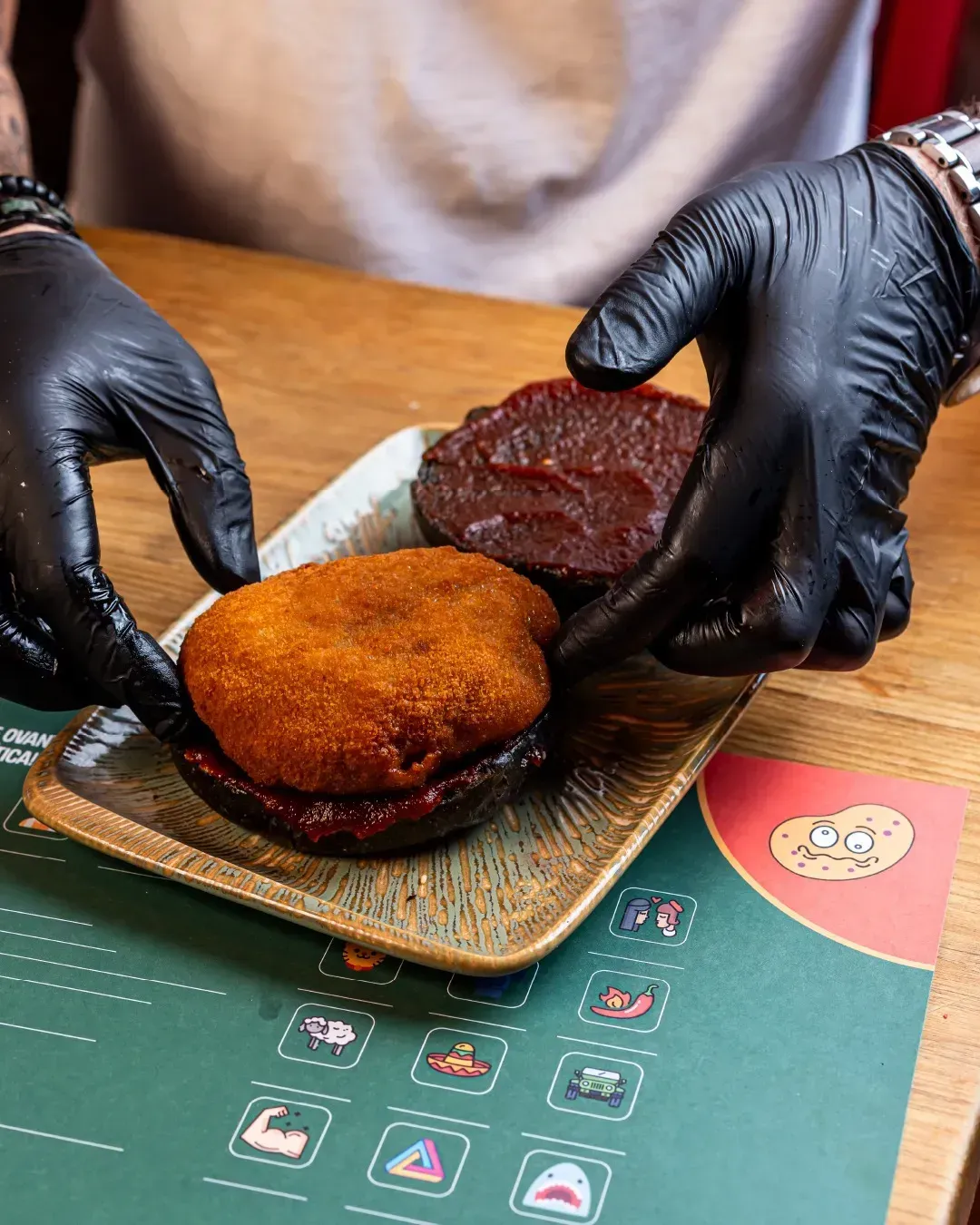 Una persona que lleva guantes negros está poniendo comida en un plato.