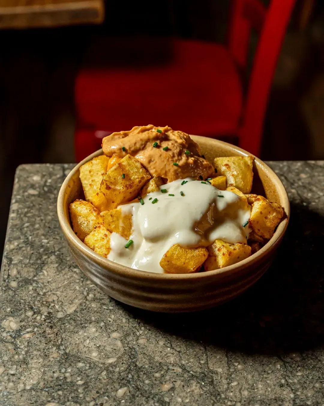 Un bol de patatas con crema agria y salsa sobre una mesa.