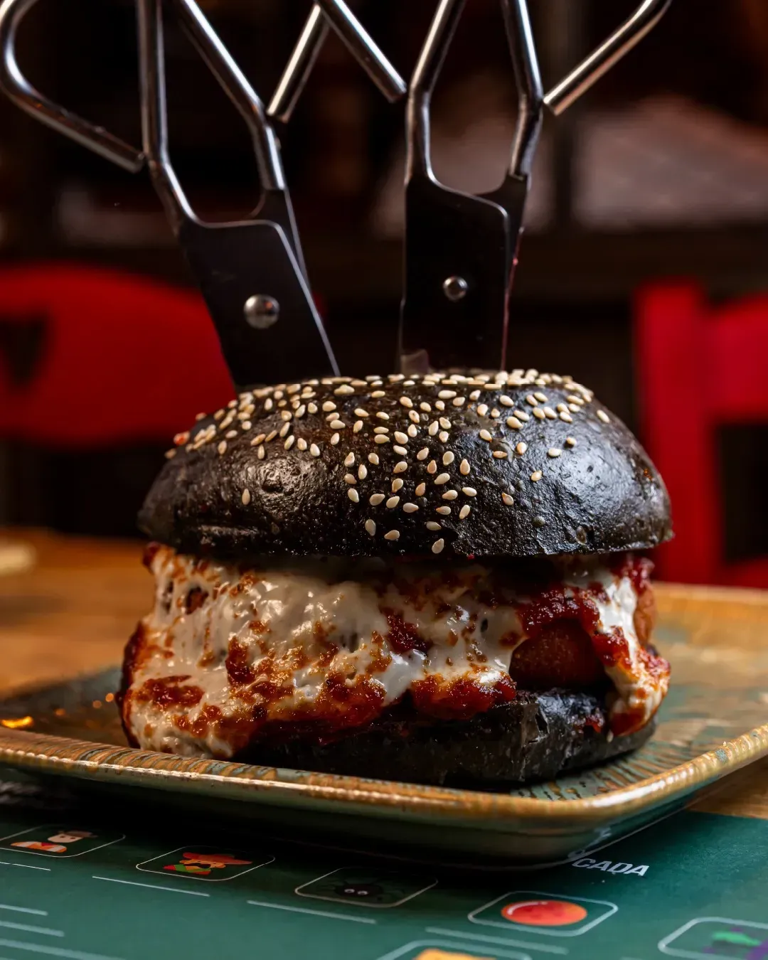 Una hamburguesa con un par de tijeras encima en un plato.