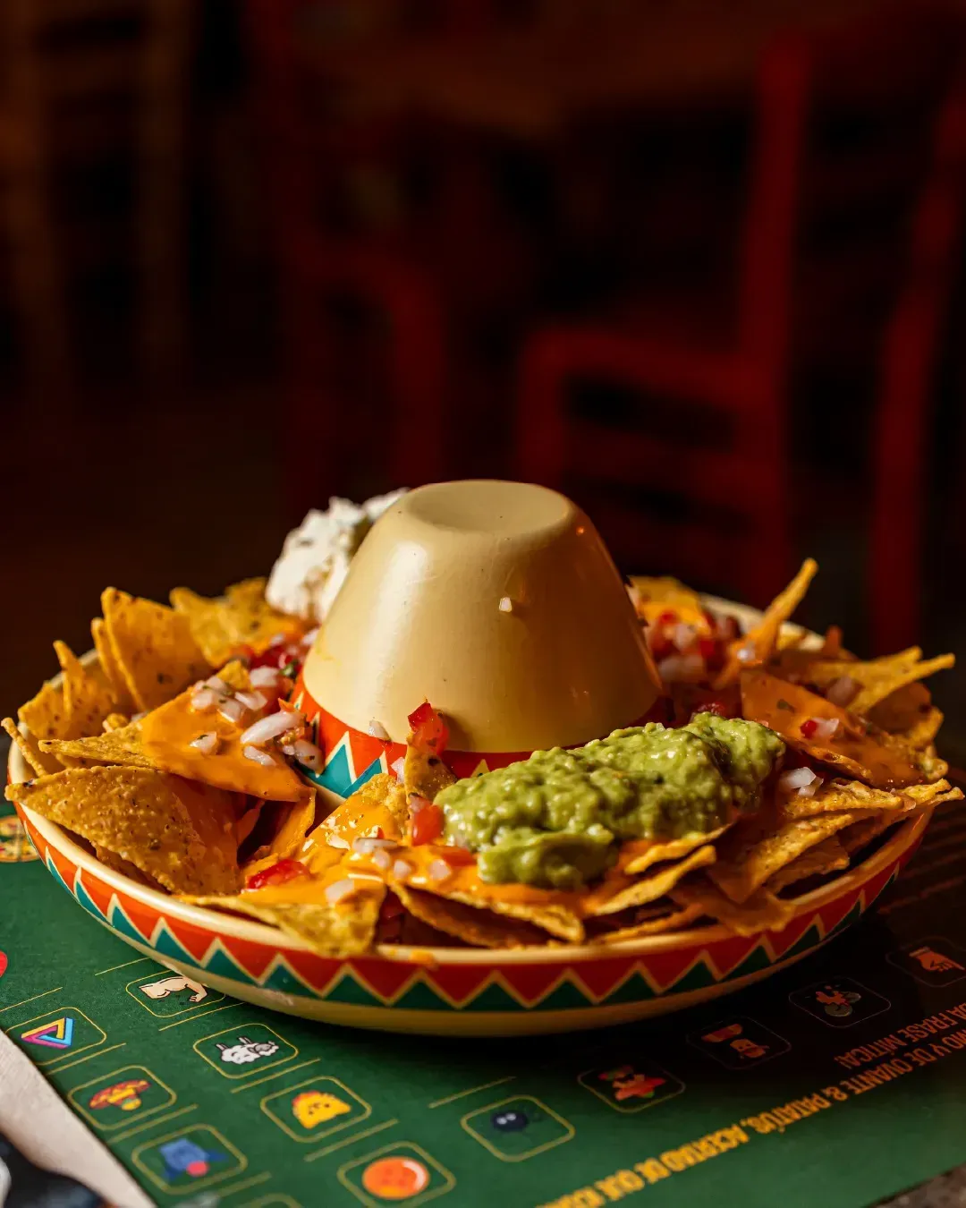 Un plato de nachos con guacamole y queso sobre una mesa.
