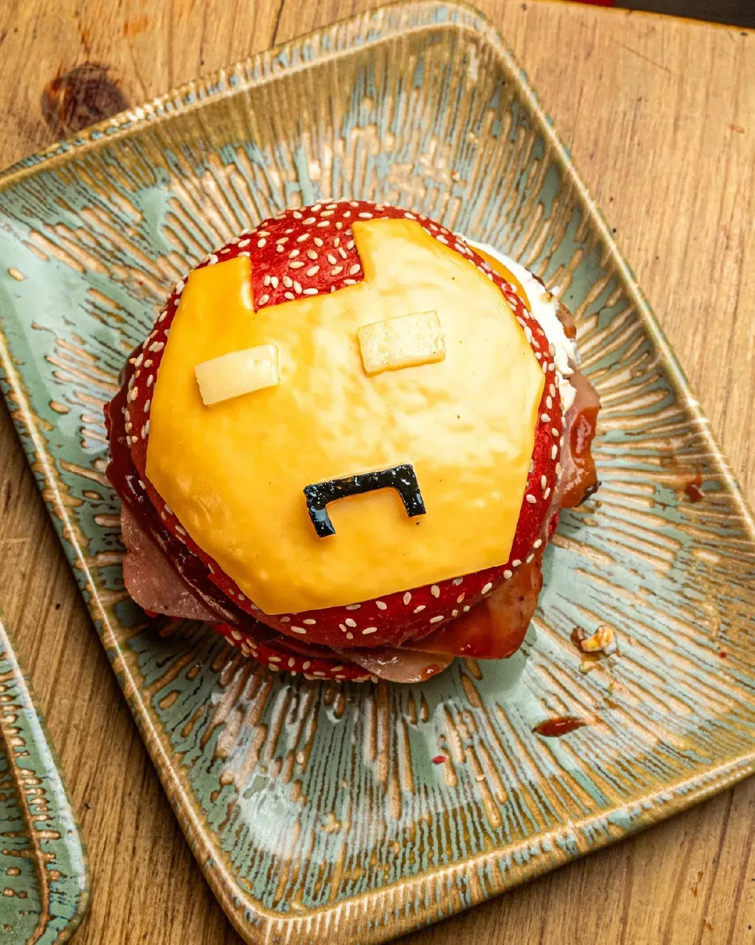 Una hamburguesa con una cara está en un plato sobre una mesa de madera.