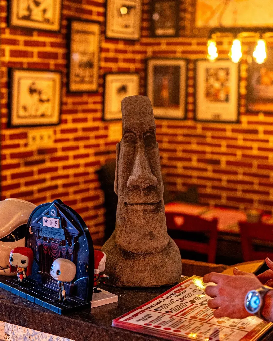 Una estatua de una cabeza de moai está sentada en un mostrador en un restaurante.