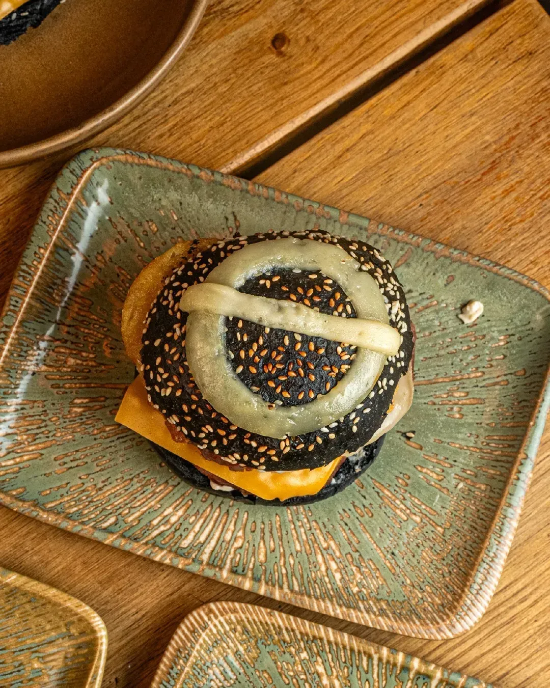 Un primer plano de una hamburguesa en un plato sobre una mesa de madera.