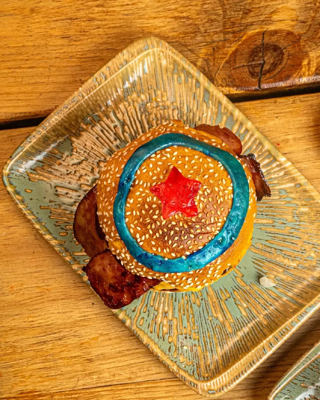 Una hamburguesa de la Mujer Maravilla está en un plato sobre una mesa de madera.