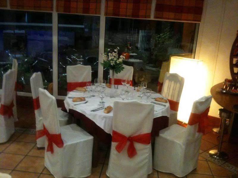 Una mesa y sillas con lazos rojos.