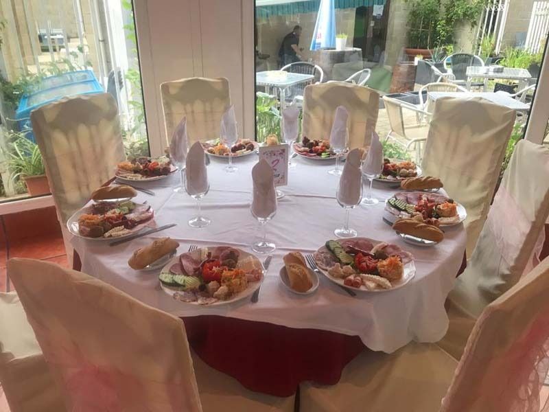 Una mesa redonda con platos de comida y copas de vino sobre ella.