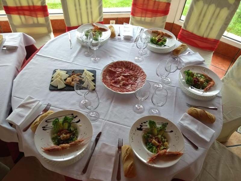Una mesa con platos de comida y copas de vino encima.
