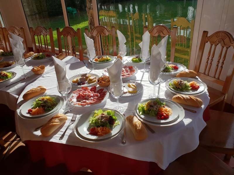Una mesa con platos de comida y copas de vino encima.