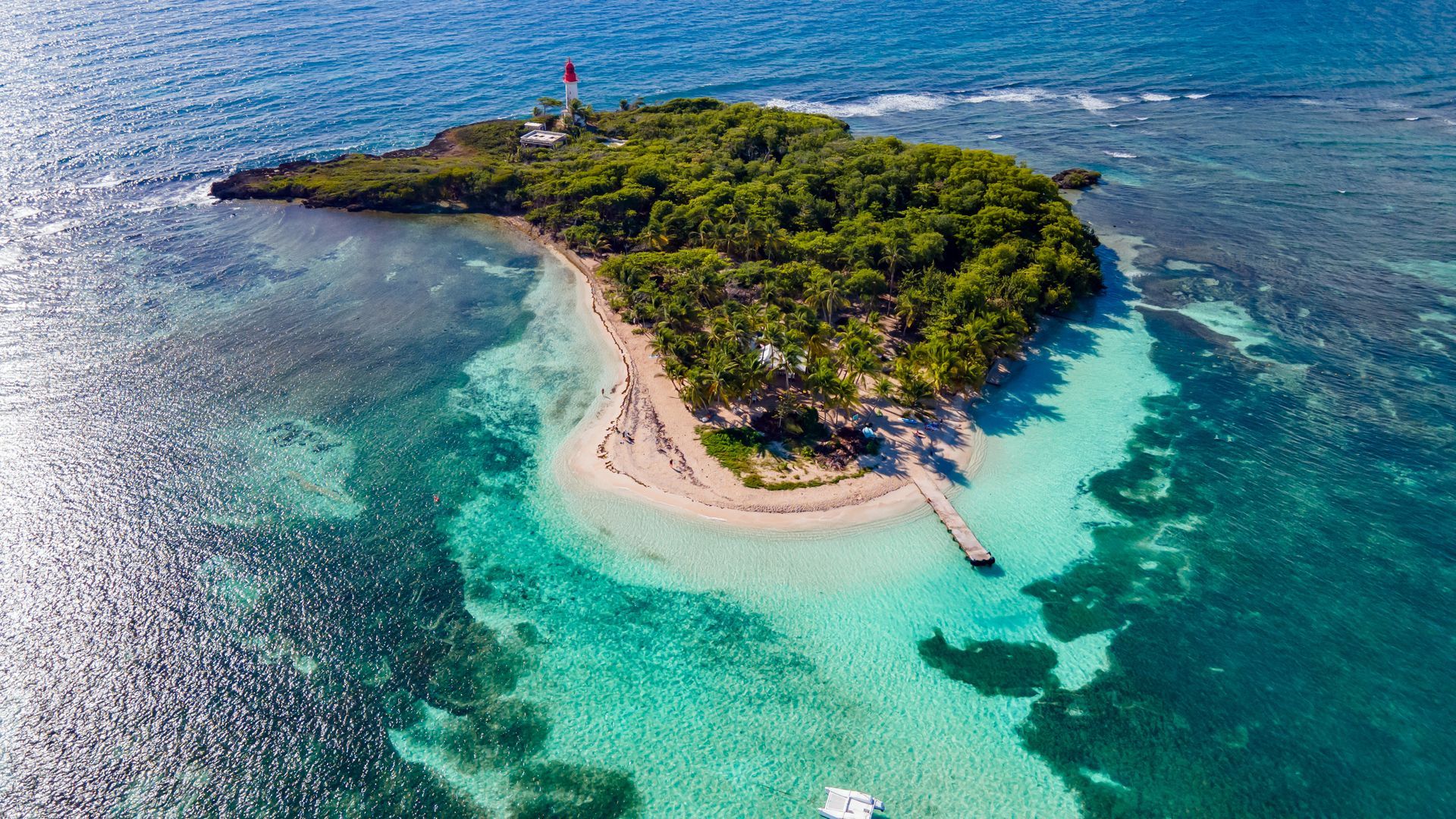 Petite île tropicale avec plage de sable fin, eau turquoise et végétation luxuriante vue du ciel