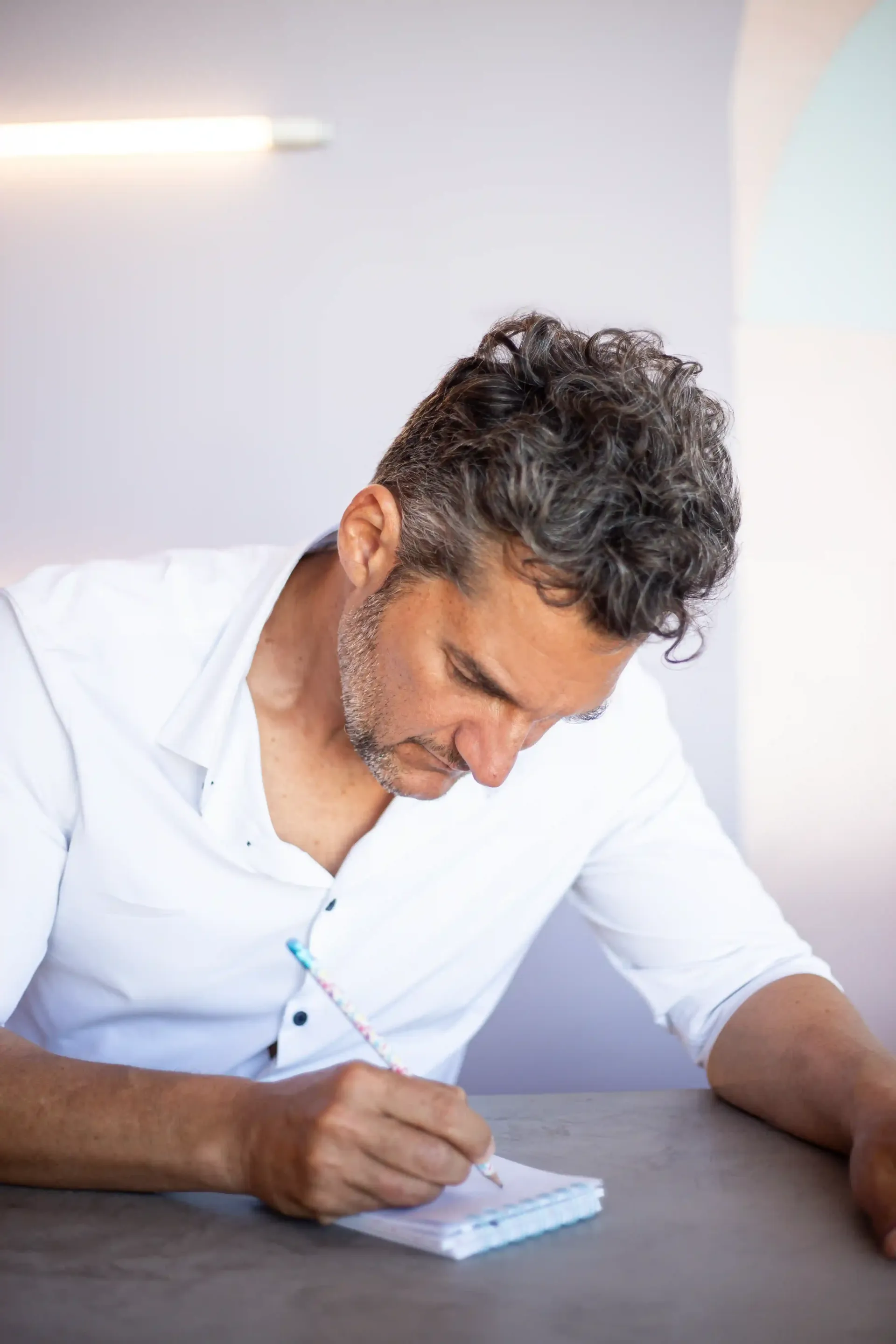 Dos personas se abrazan contra una pared amarilla lisa, sonriéndose mutuamente.