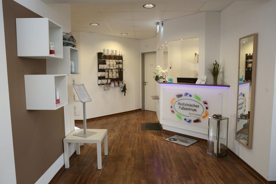 Empfangsbereich mit Rezeption, Regalen und Holzboden.