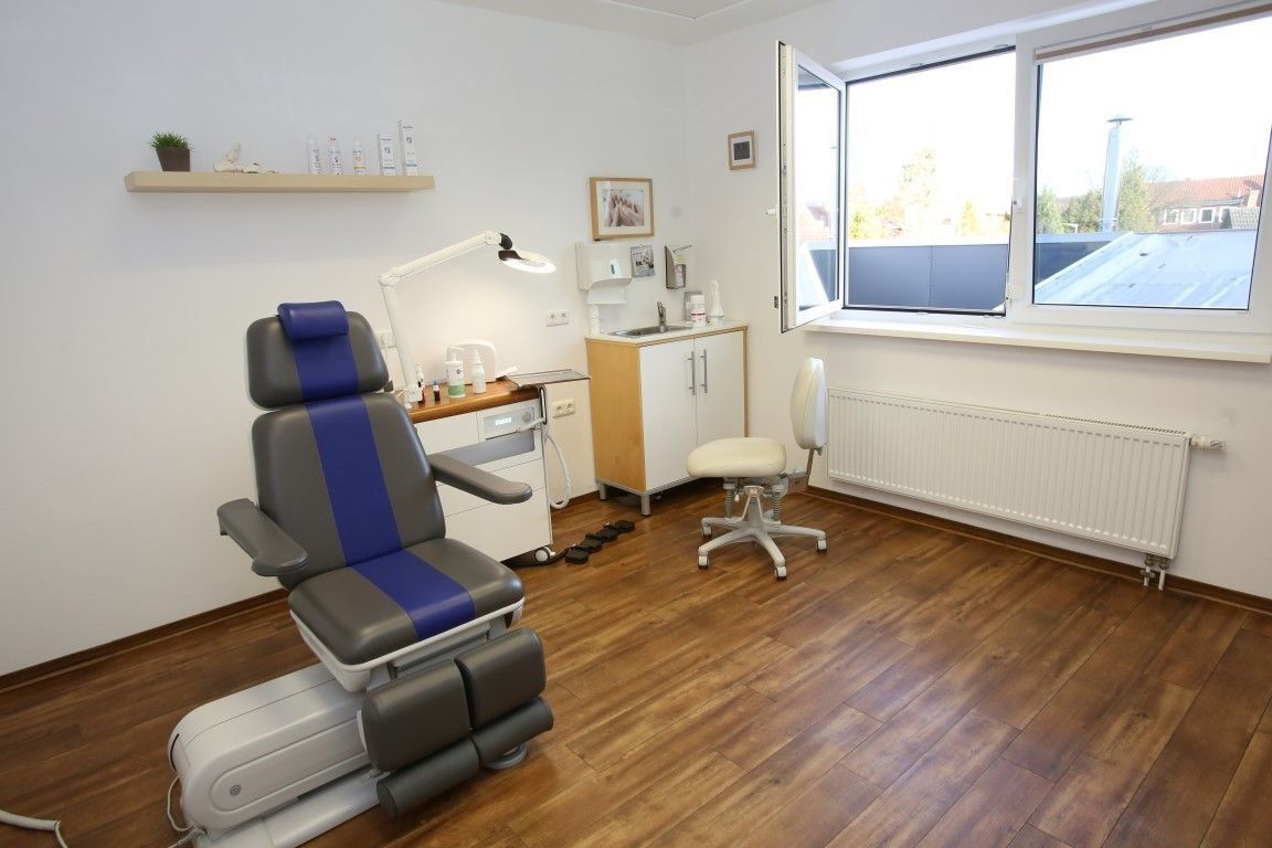 Podologieraum mit Patientenstuhl, Instrumenten und Fenster.