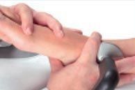 Manos que sostienen y masajean el antebrazo de una persona con una herramienta gris sobre un fondo blanco.