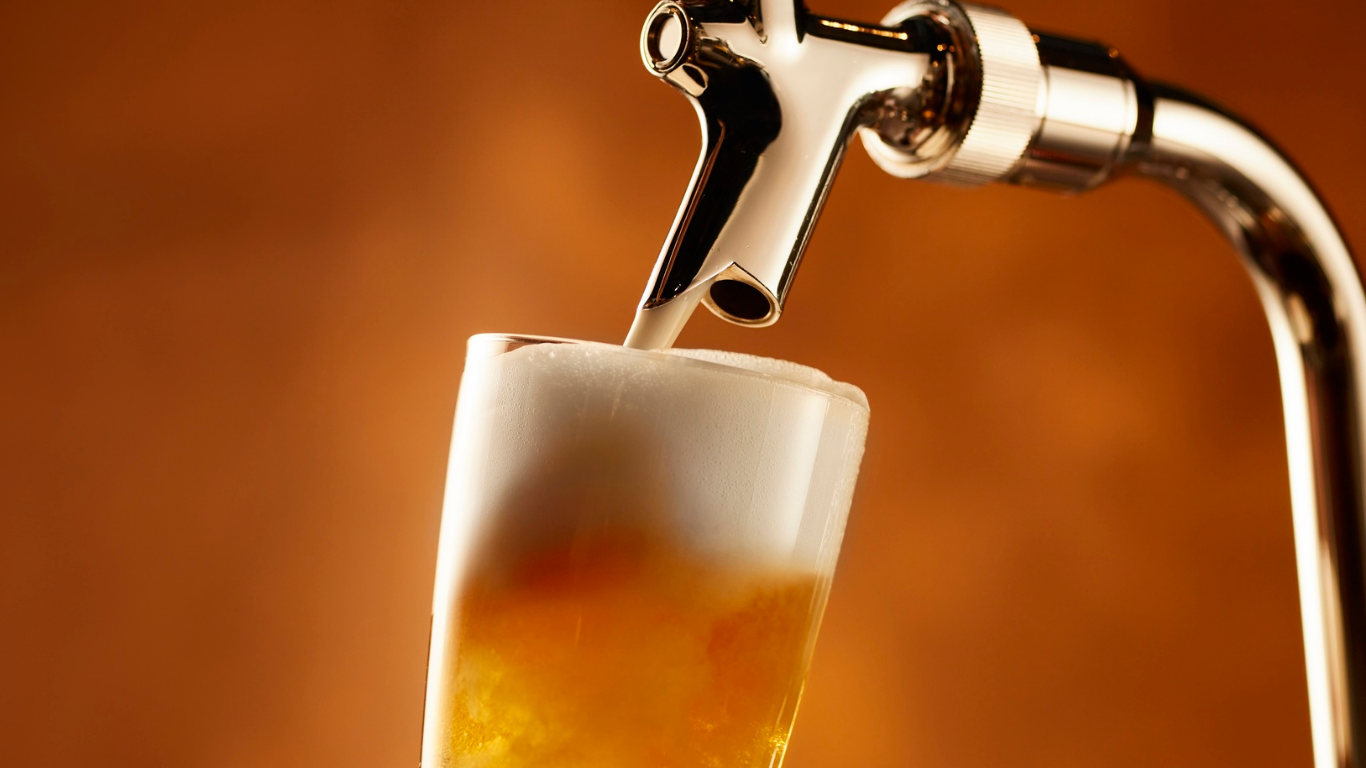 Cerveza vertida desde un grifo a un vaso, creando una espuma.
