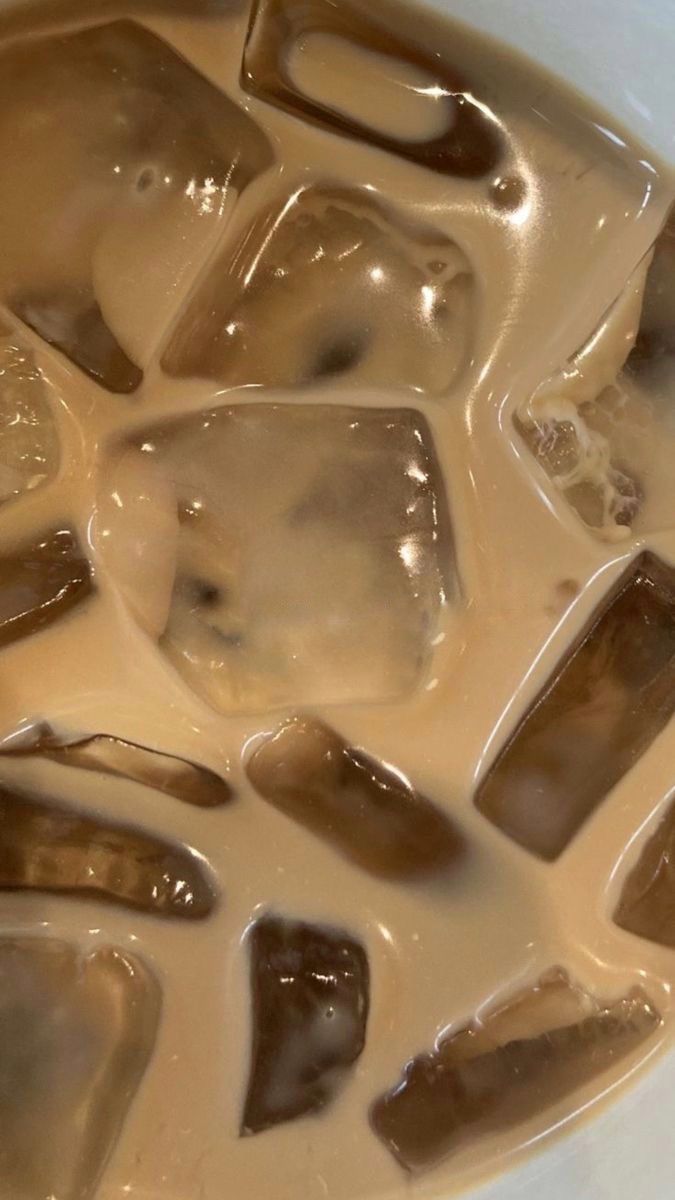 Café helado con cubitos de hielo, en primer plano, líquido cremoso de color bronce.